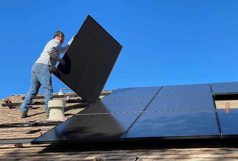 Người đàn ông lắp đặt các tấm pin mặt trời trên mái nhà